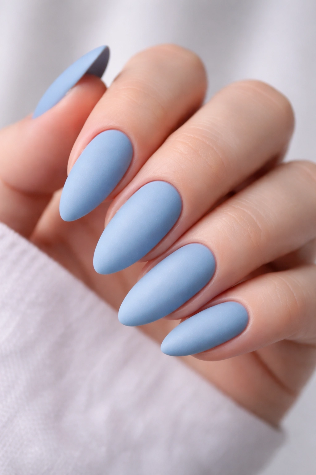 Close-up of matte blue acrylic nails in studio lighting