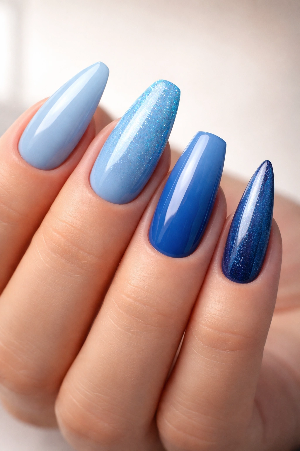 Hand showing blue acrylic nails in almond, oval, square, and stiletto shapes