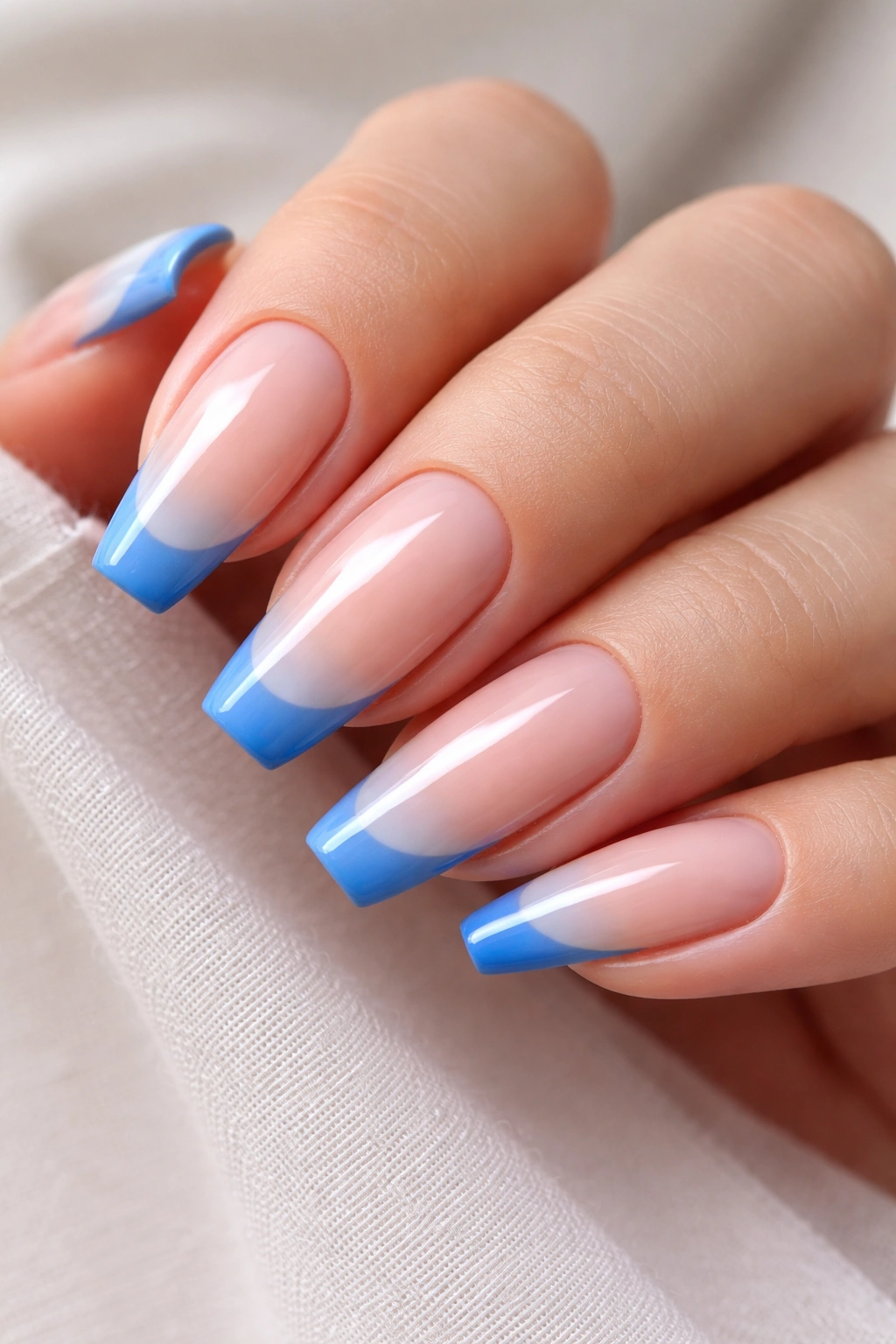 Nude-based nails with blue tips close-up in studio