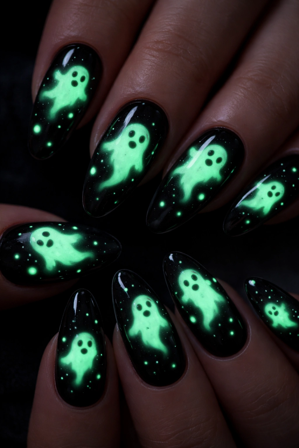 Close-up of jet-black nails with glowing ghost designs in the dark