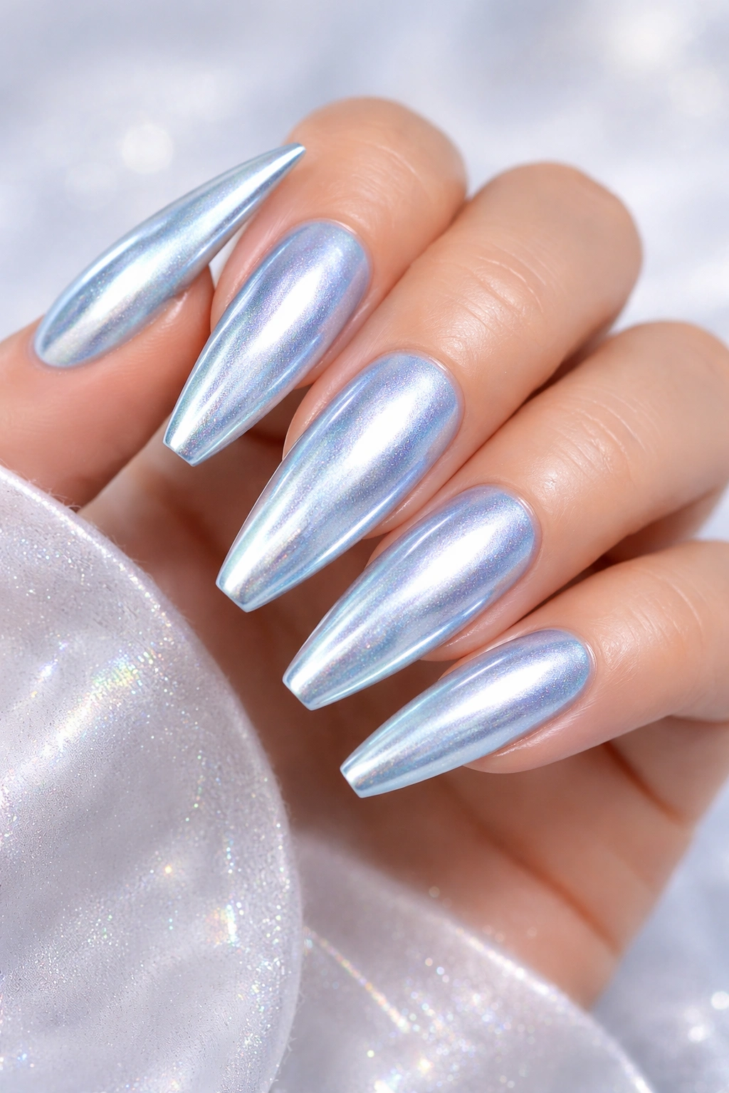 Close-up of ice blue chrome nails with reflective finish on a neutral background