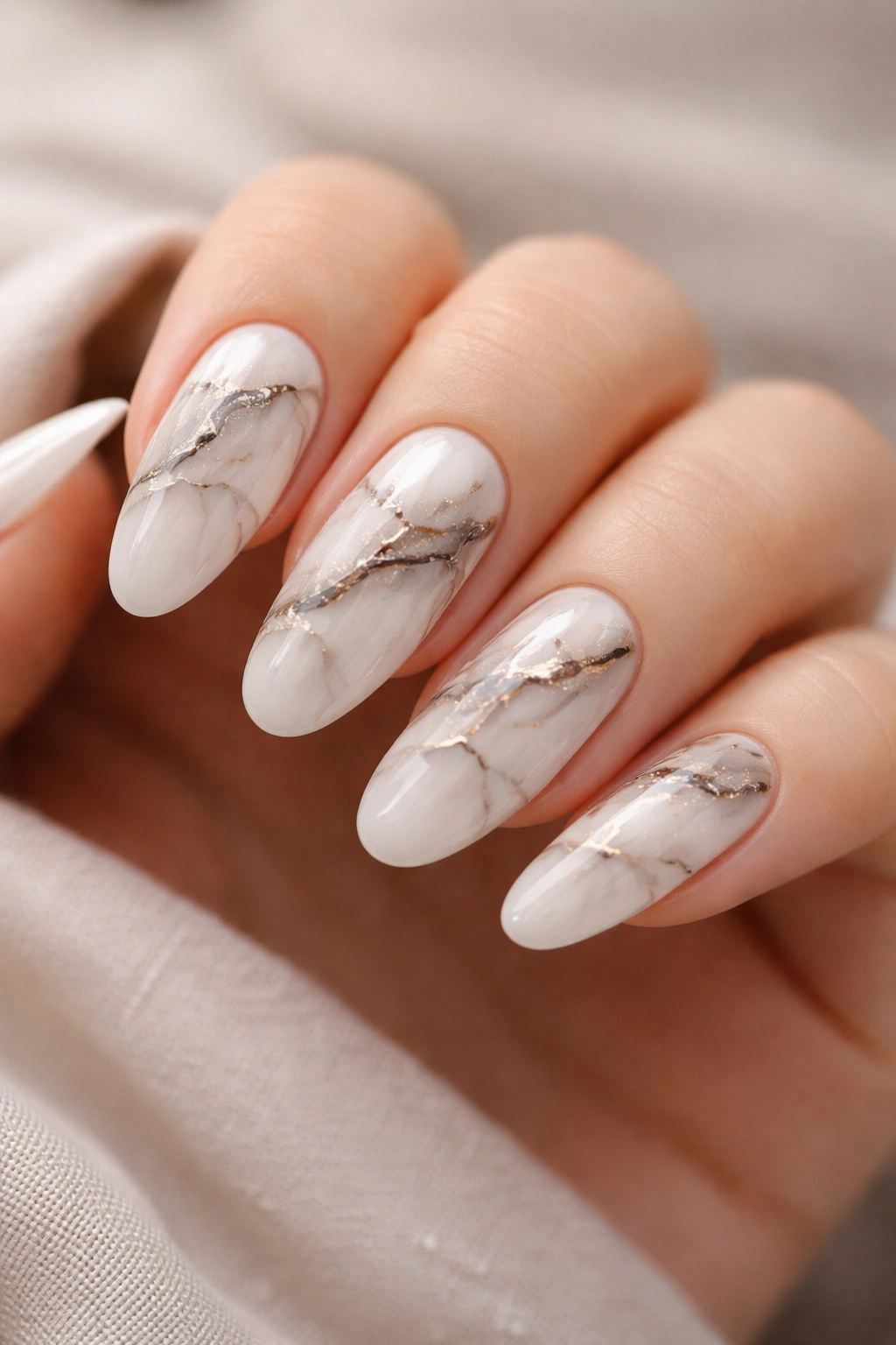 Close-up of long round acrylic nails with a refined marble design in neutral tones
