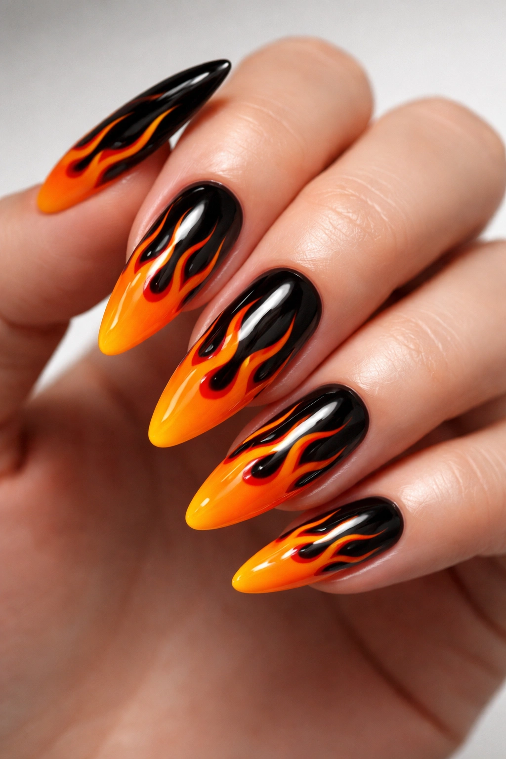 Close-up of orange and black flame nails with irregular flame shapes