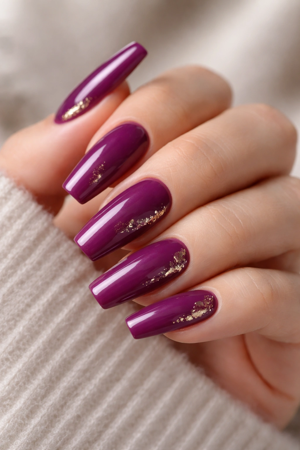 Close-up of berry purple ballerina nails with subtle gold foil accents