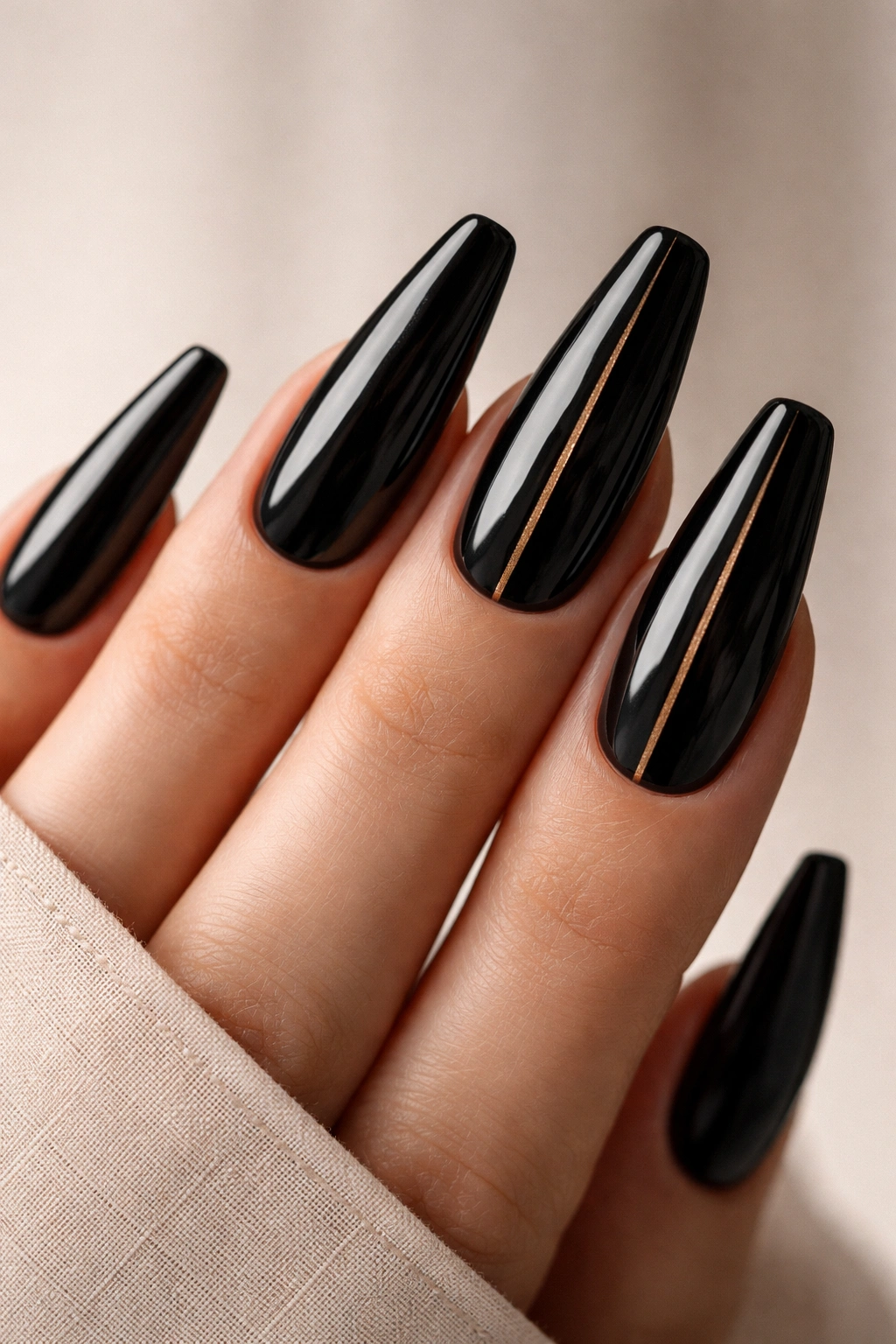 Close-up of black patent ballerina nails with a thin gold line on accent nails