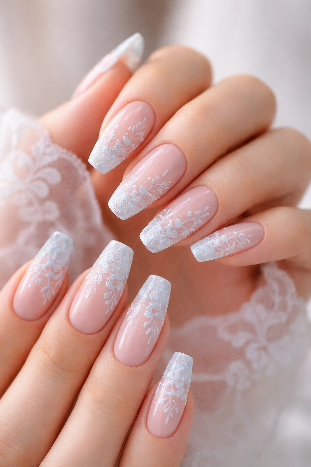 Close-up of nails with blue floral lace over a sheer nude base on accent nails, airy and delicate