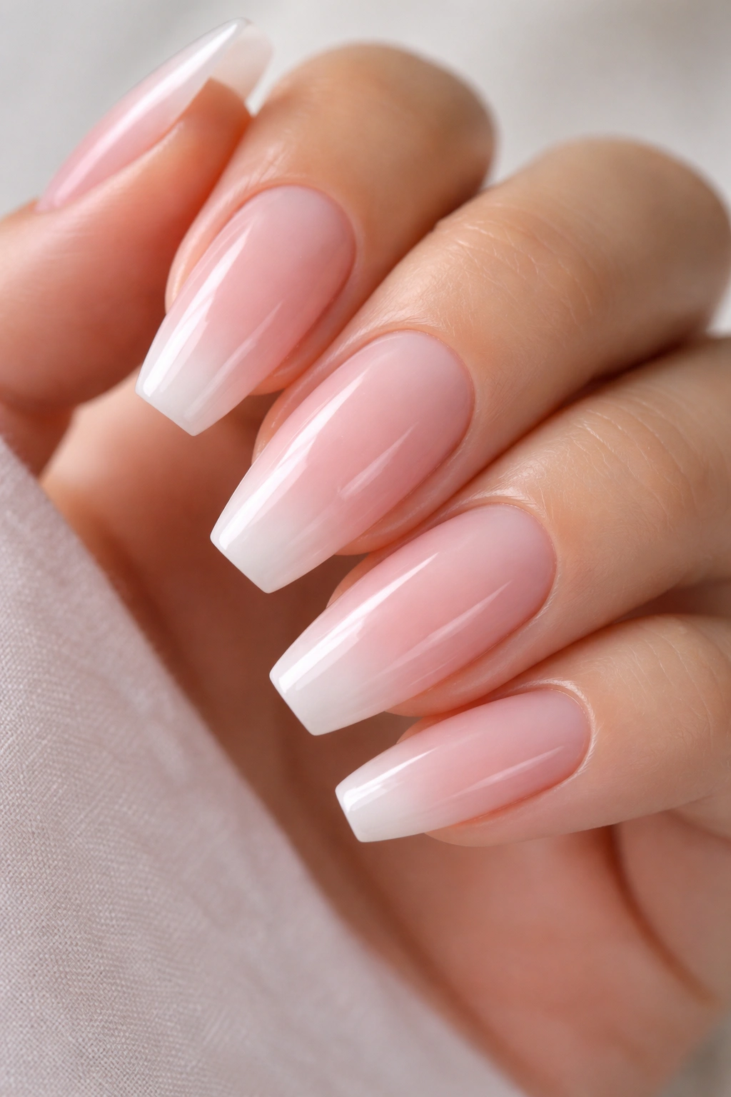 Nail close-up with glossy baby pink and white fade on ballerina nails