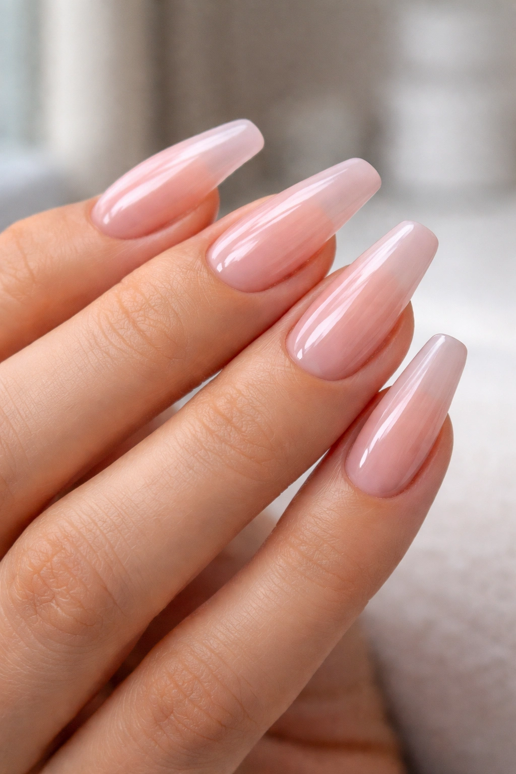 Glossy sheer pink nails on a hand