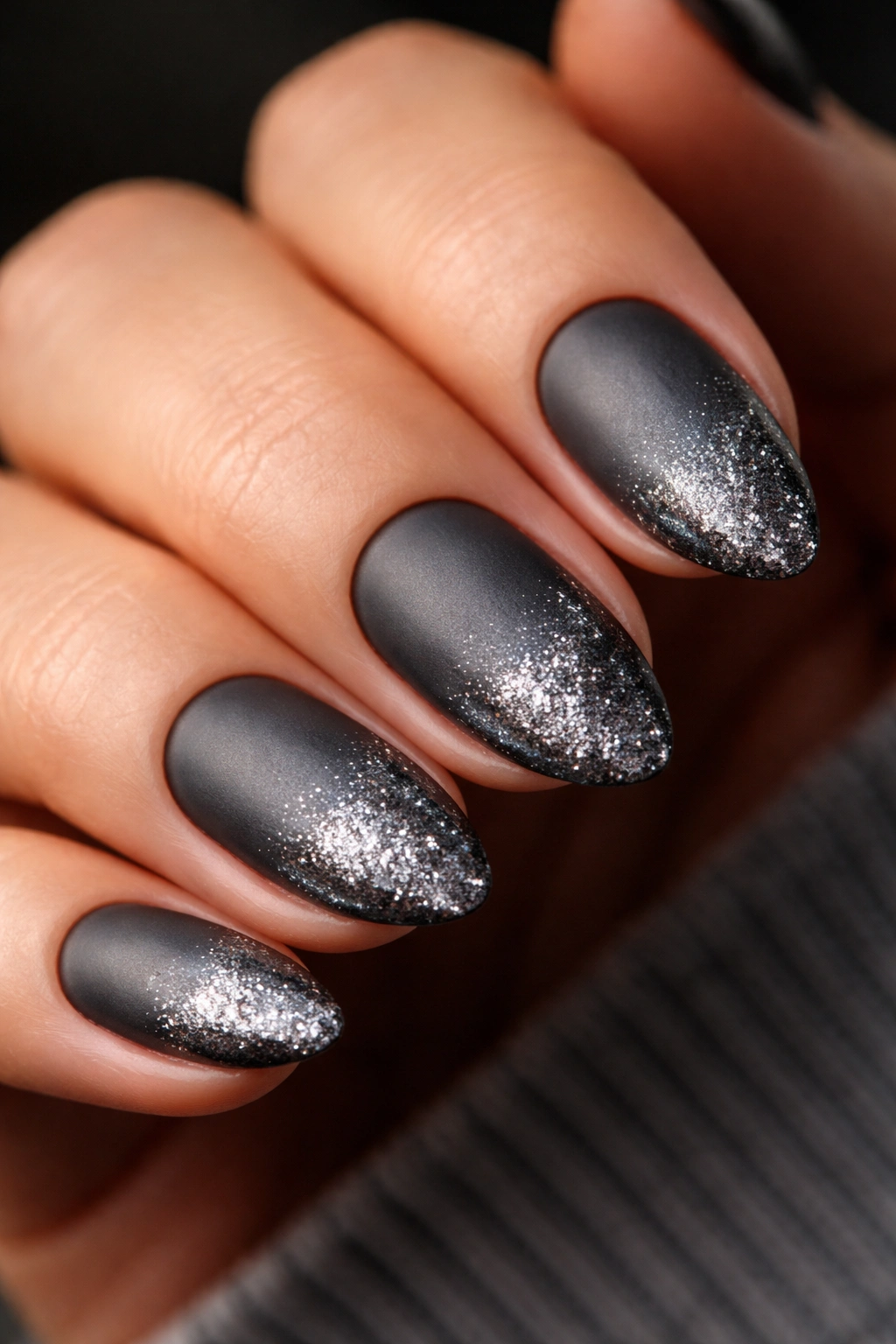 Close-up of gunmetal glitter nails with matte-gloss finish on short almonds