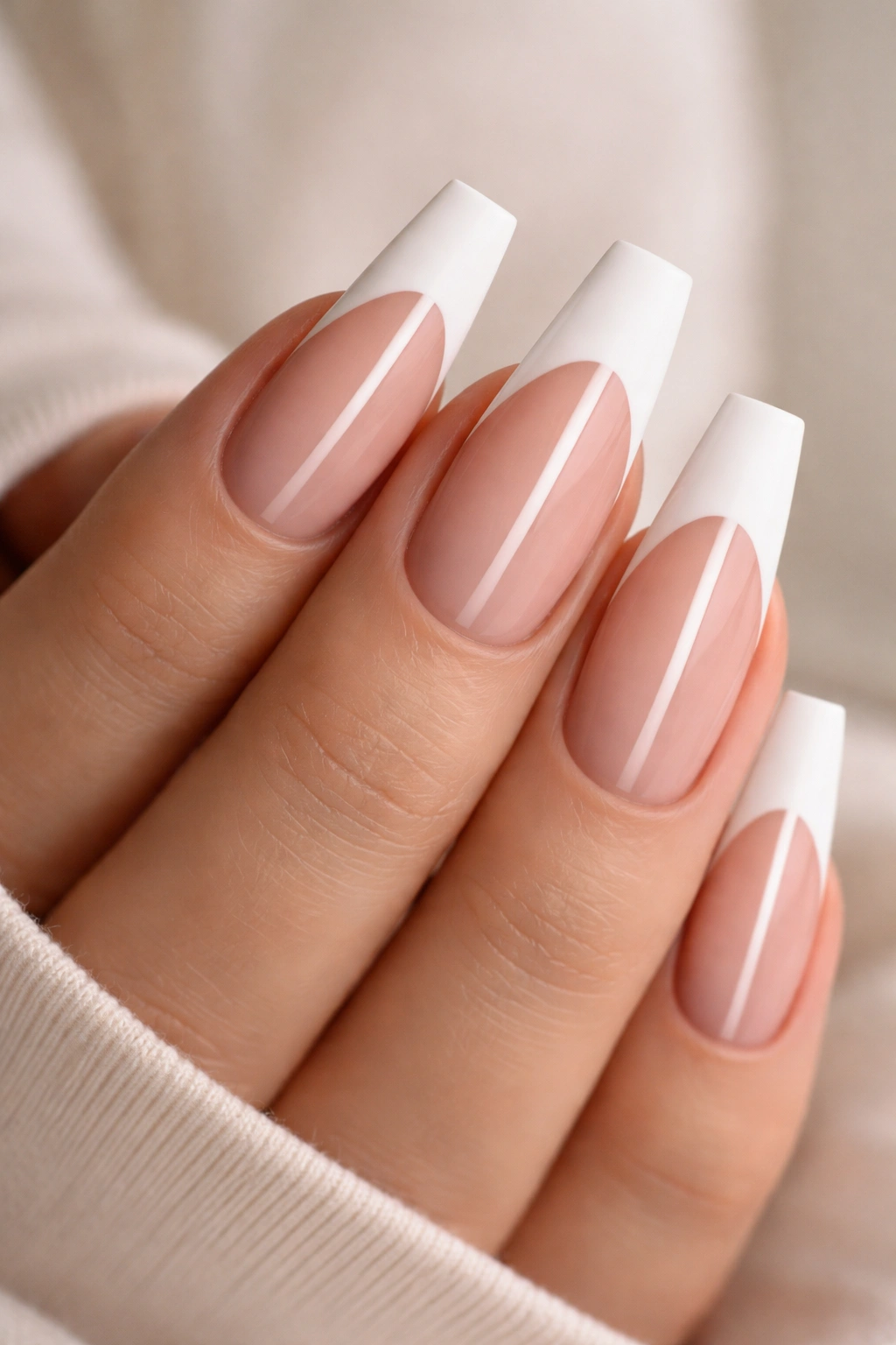 Close-up of coffin nails with matte white tips on nude base and glossy central stripe