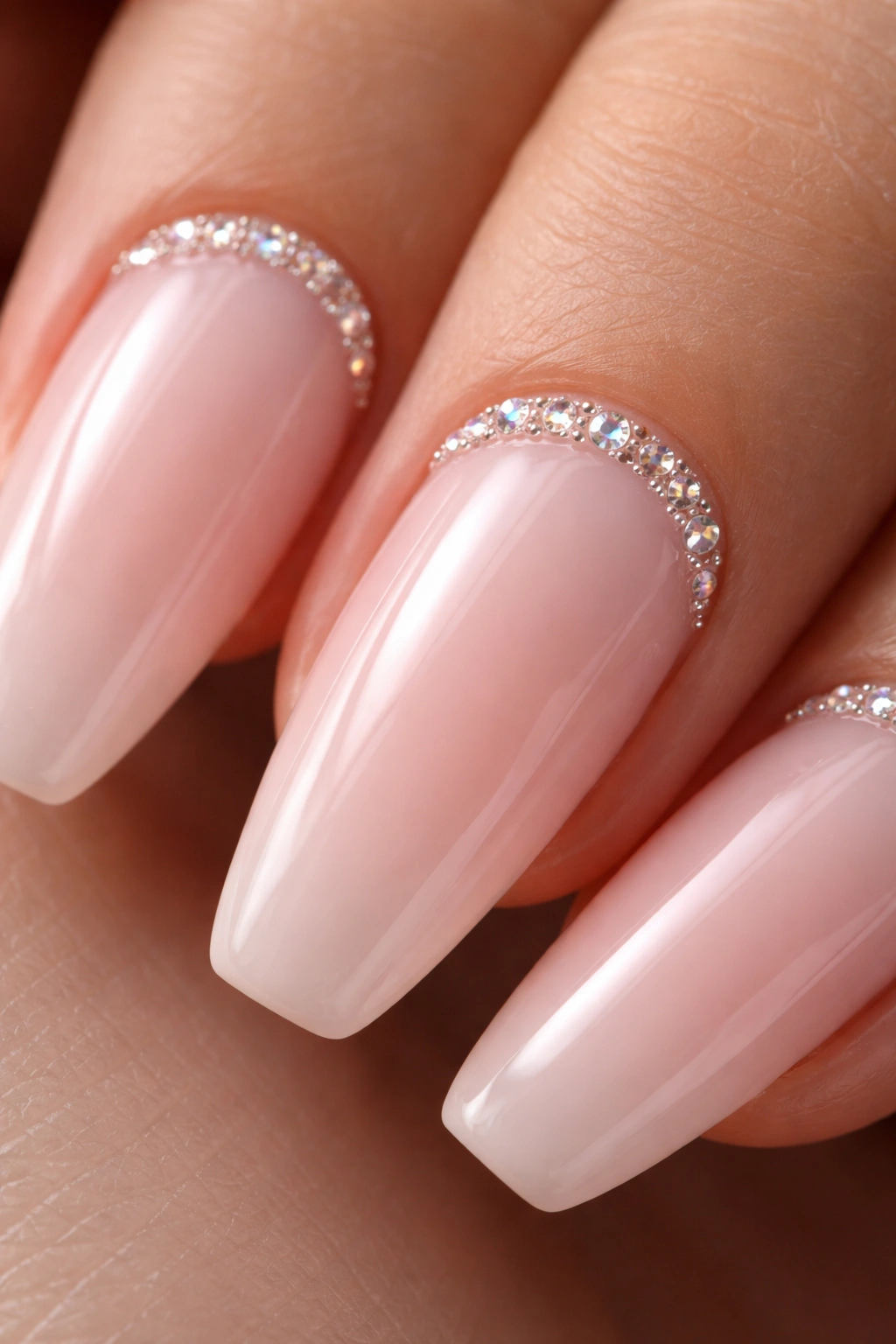 Milky pink nail base with crystal crescent near cuticle on ballerina nails.