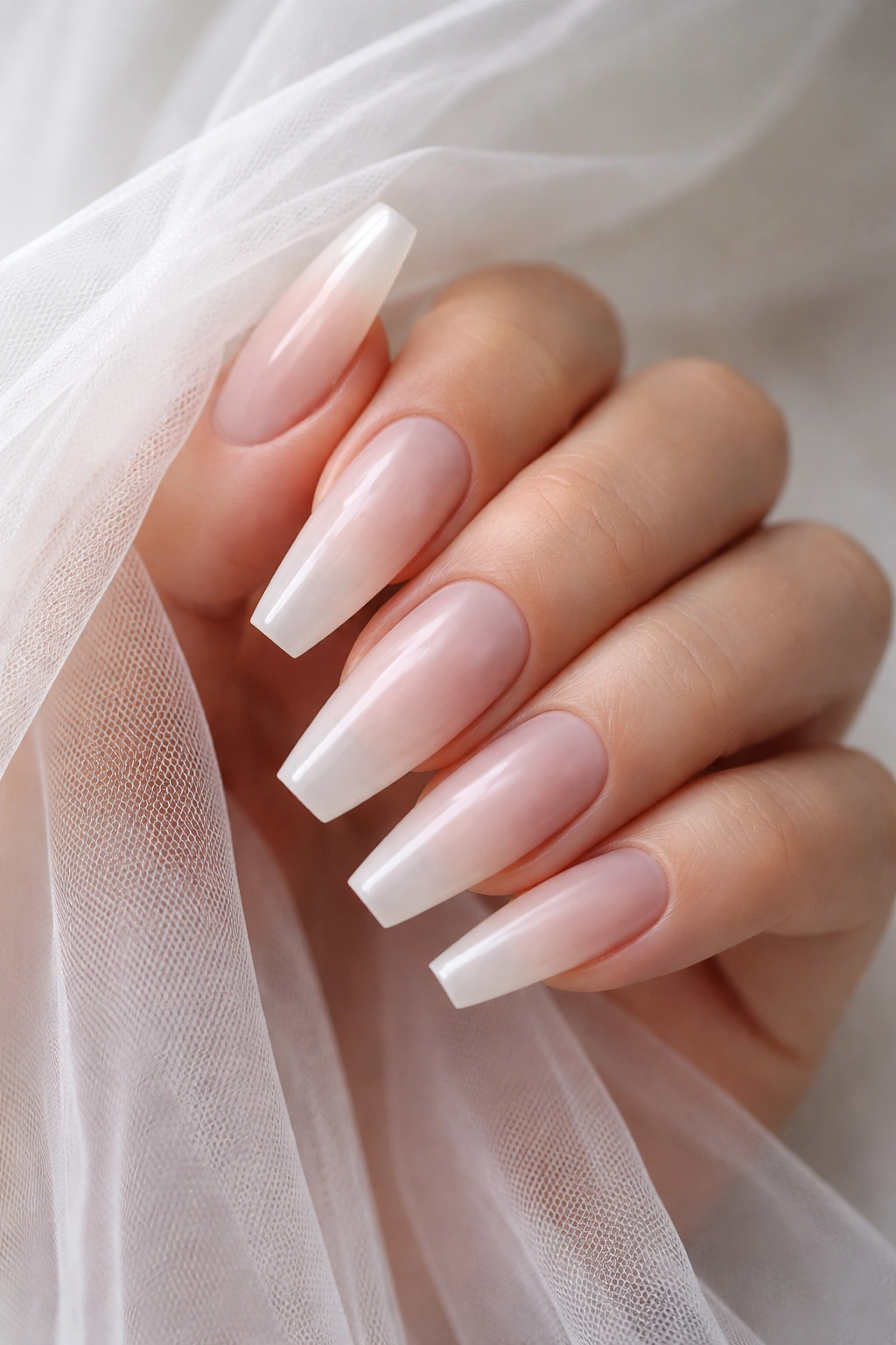 Milky clear ballerina nails with a sheer white veil for a frosted translucent look.