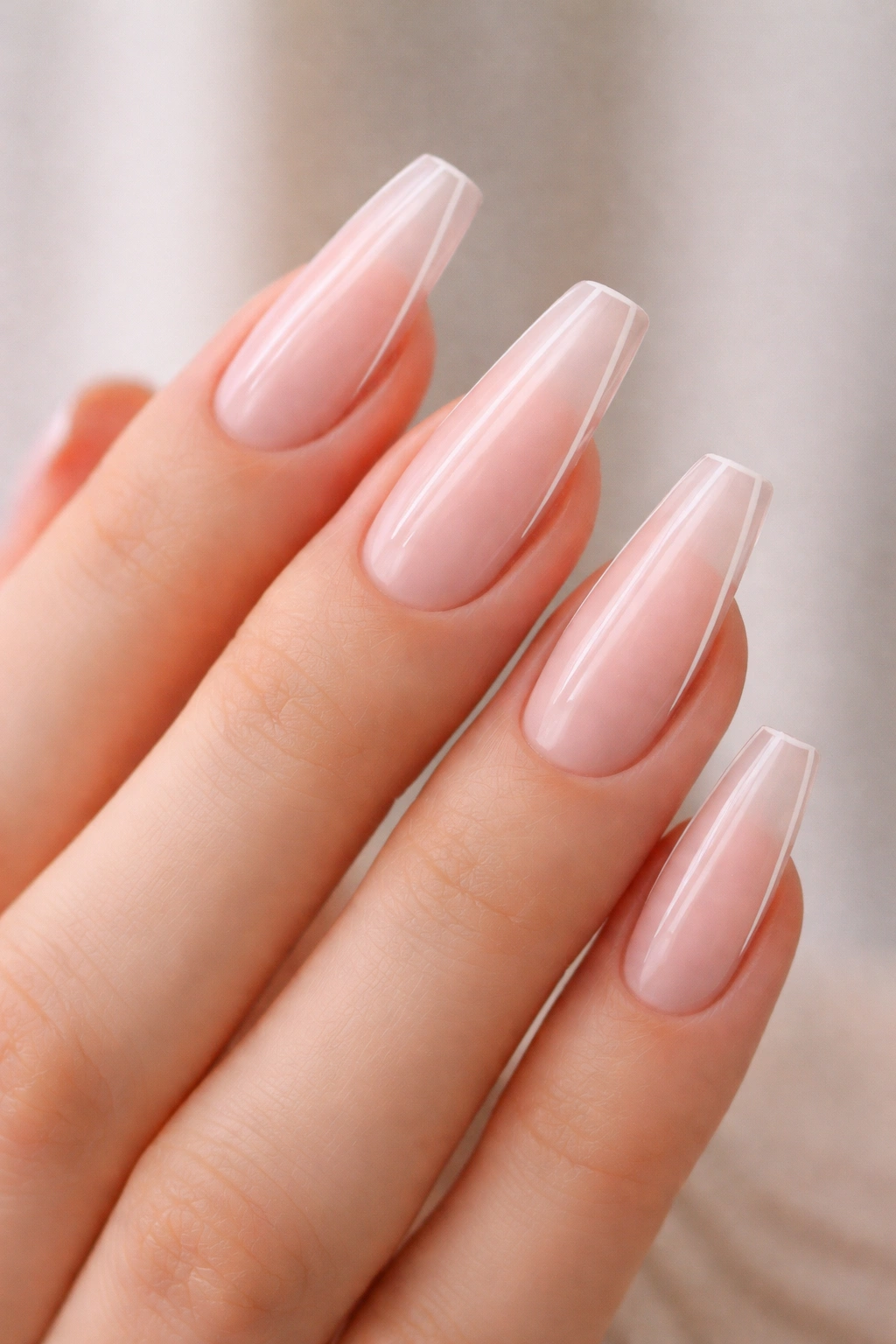 Close-up of milky pink nails with whisper-thin side outlines on a hand.