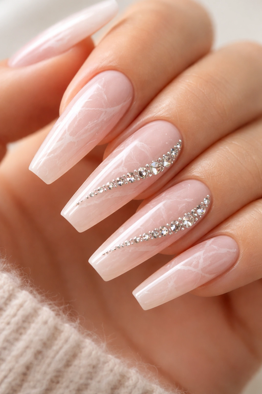 Nude-pink marble nails with a diagonal crystal sweep along two to three nails.