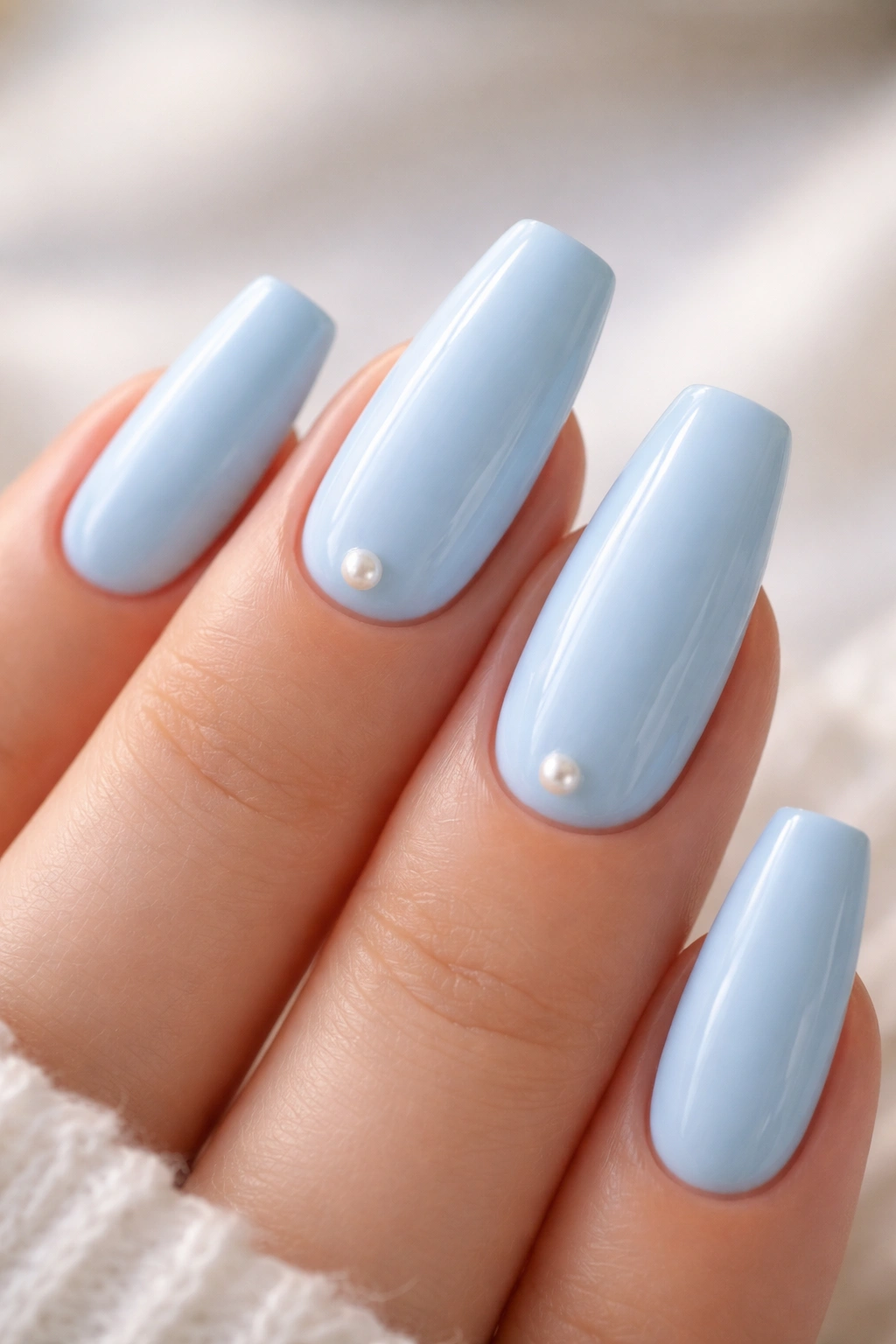 Nails with tiny pearl accents on a soft blue manicure