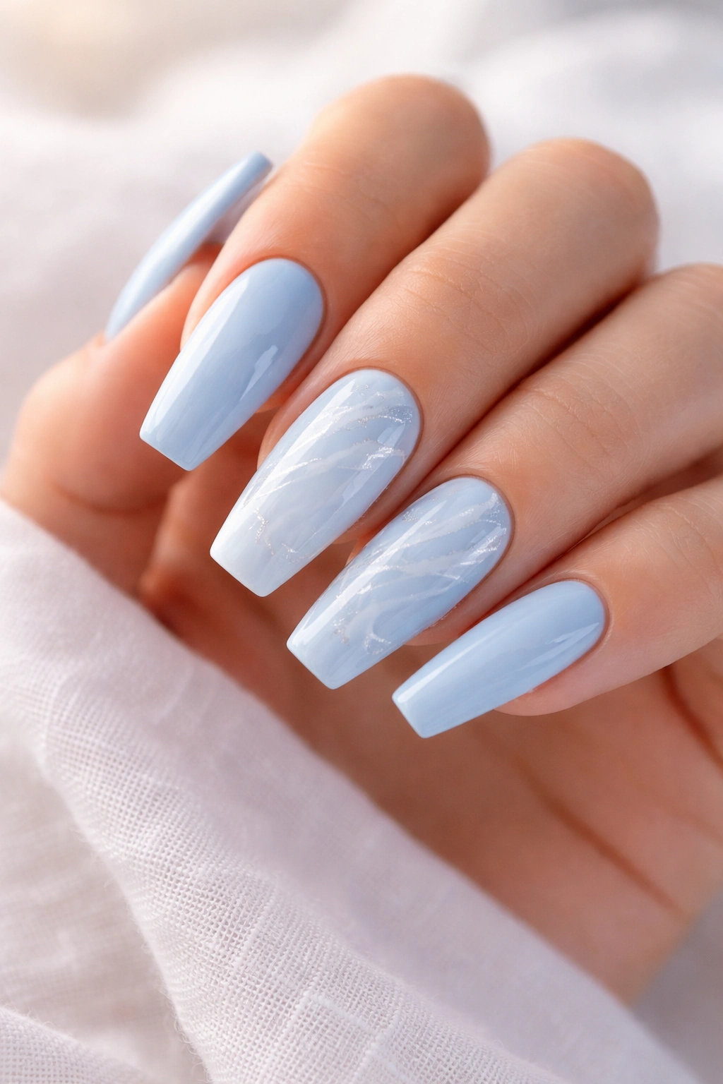 Close-up of powder blue ballerina nails with white marble swirls and subtle veining