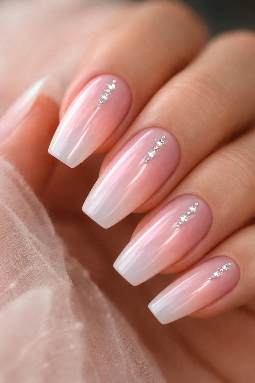 Sheer pink nails with an aura glow and a centered line of gems.