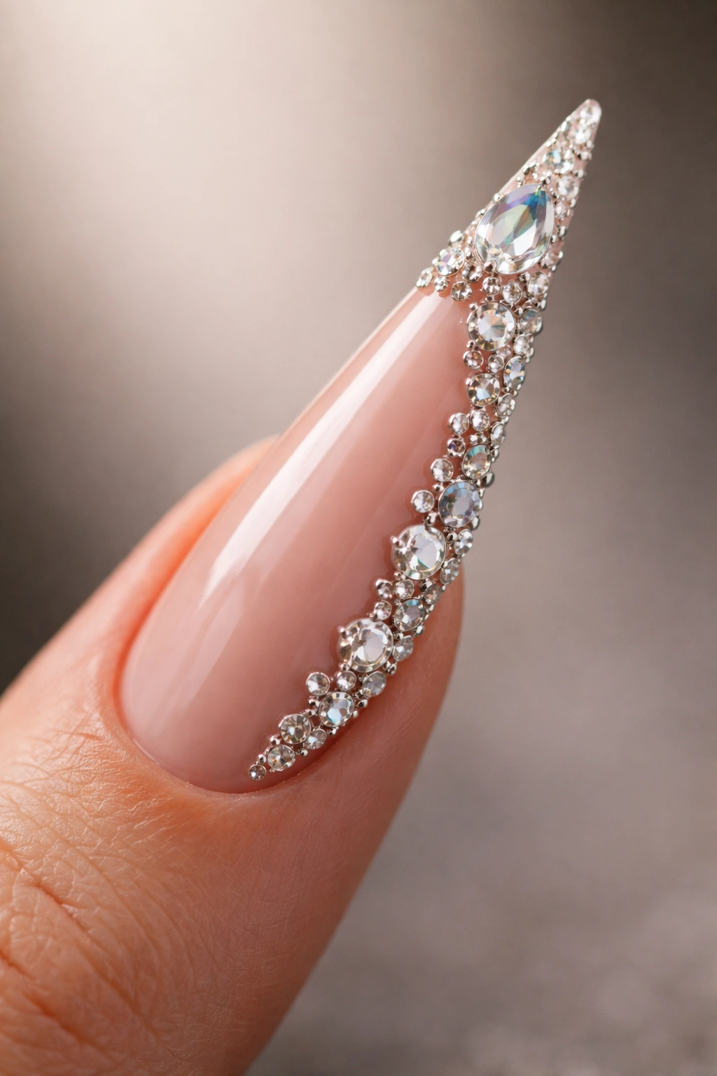 Stiletto nail with strategic 3D crystals along the outer edge toward the tip on a nude base
