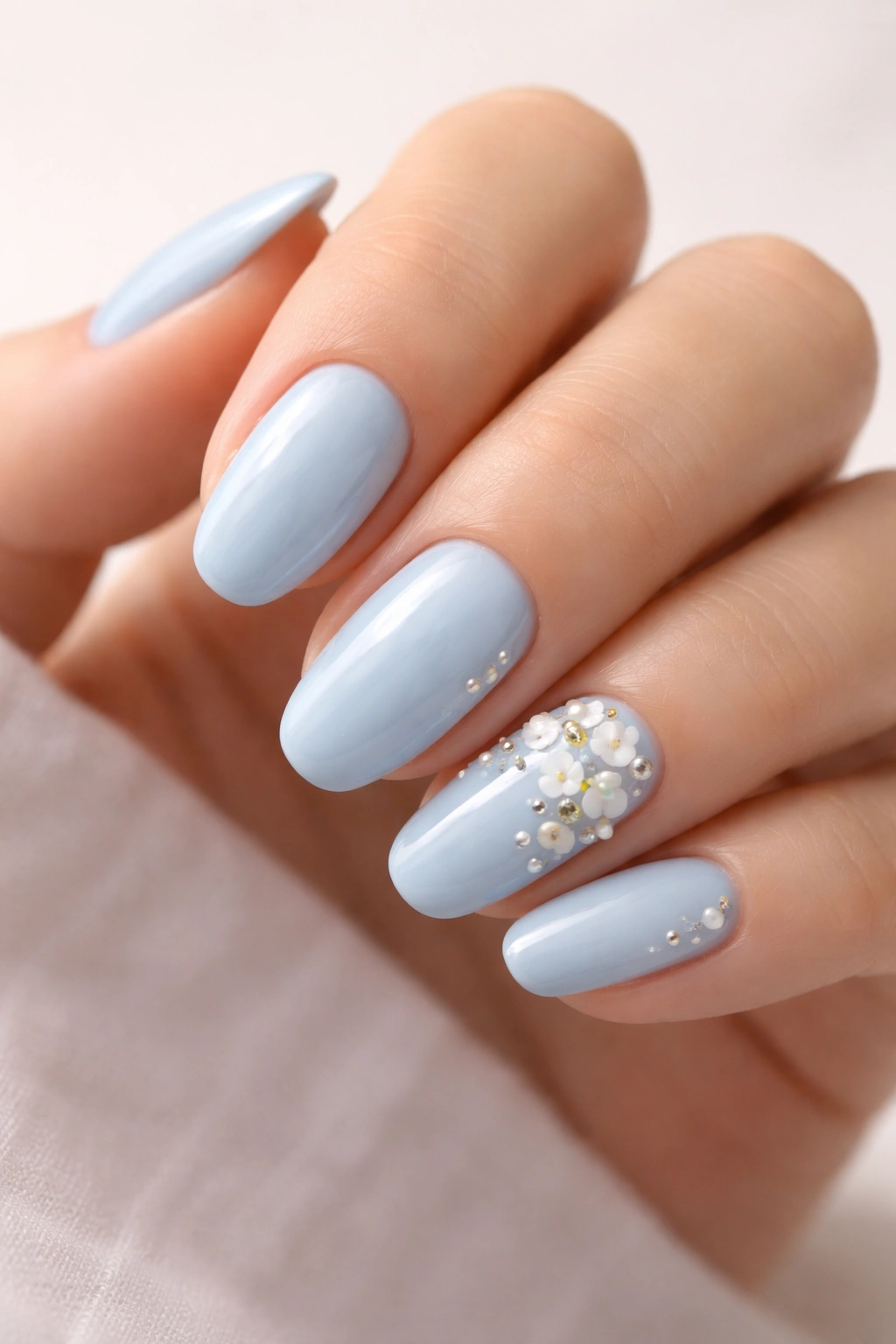 Nails with light blue polish and tiny 3D floral and pearl accents