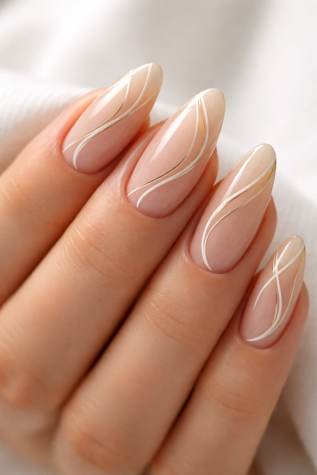 Almond nails with nude base and abstract white and gold swirl lines