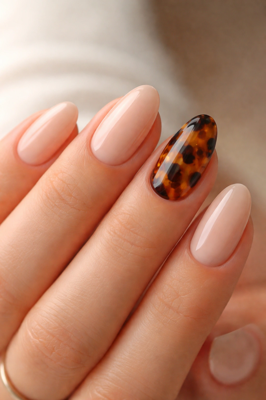 Nude almond nails with a tiny tortoiseshell accent nail