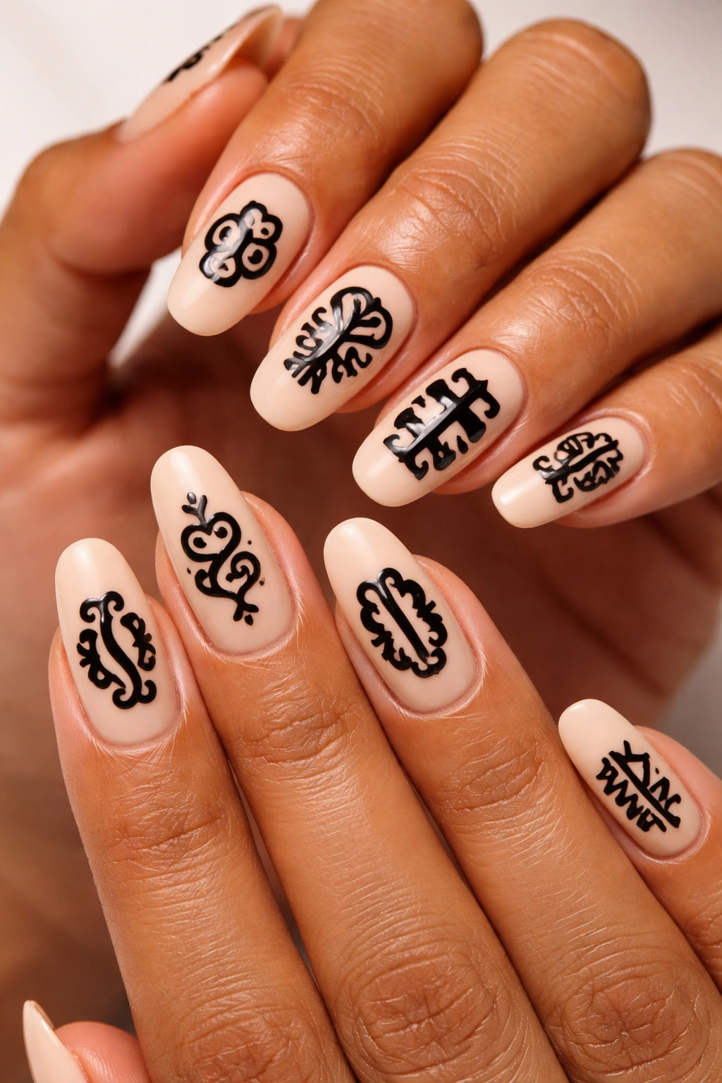 Close-up of nails featuring Adinkra symbols in black on a cream base