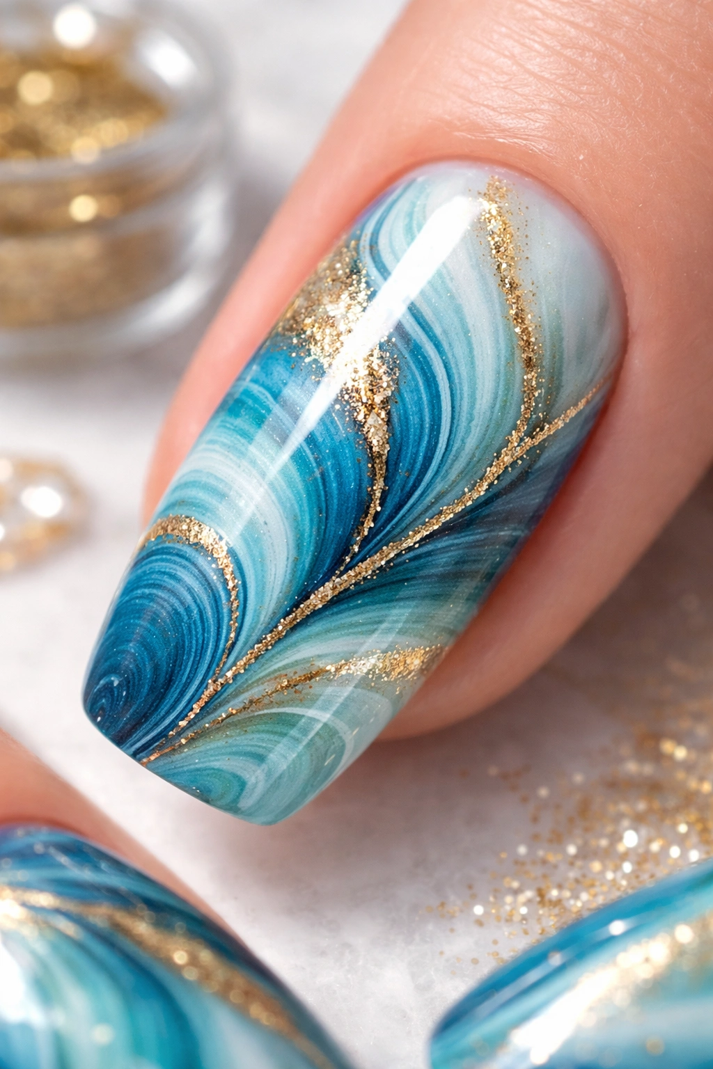 Close-up fingernail with blue gradient marble and metallic gold accent