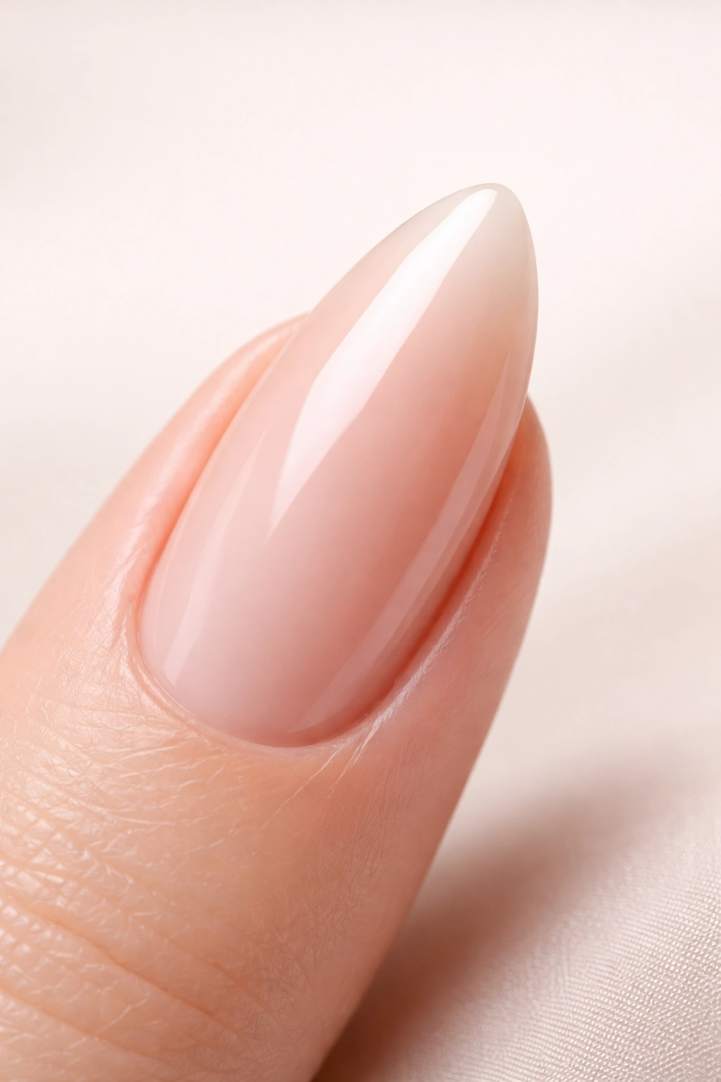 Close-up of a glossy almond-shaped acrylic nail on a neutral background