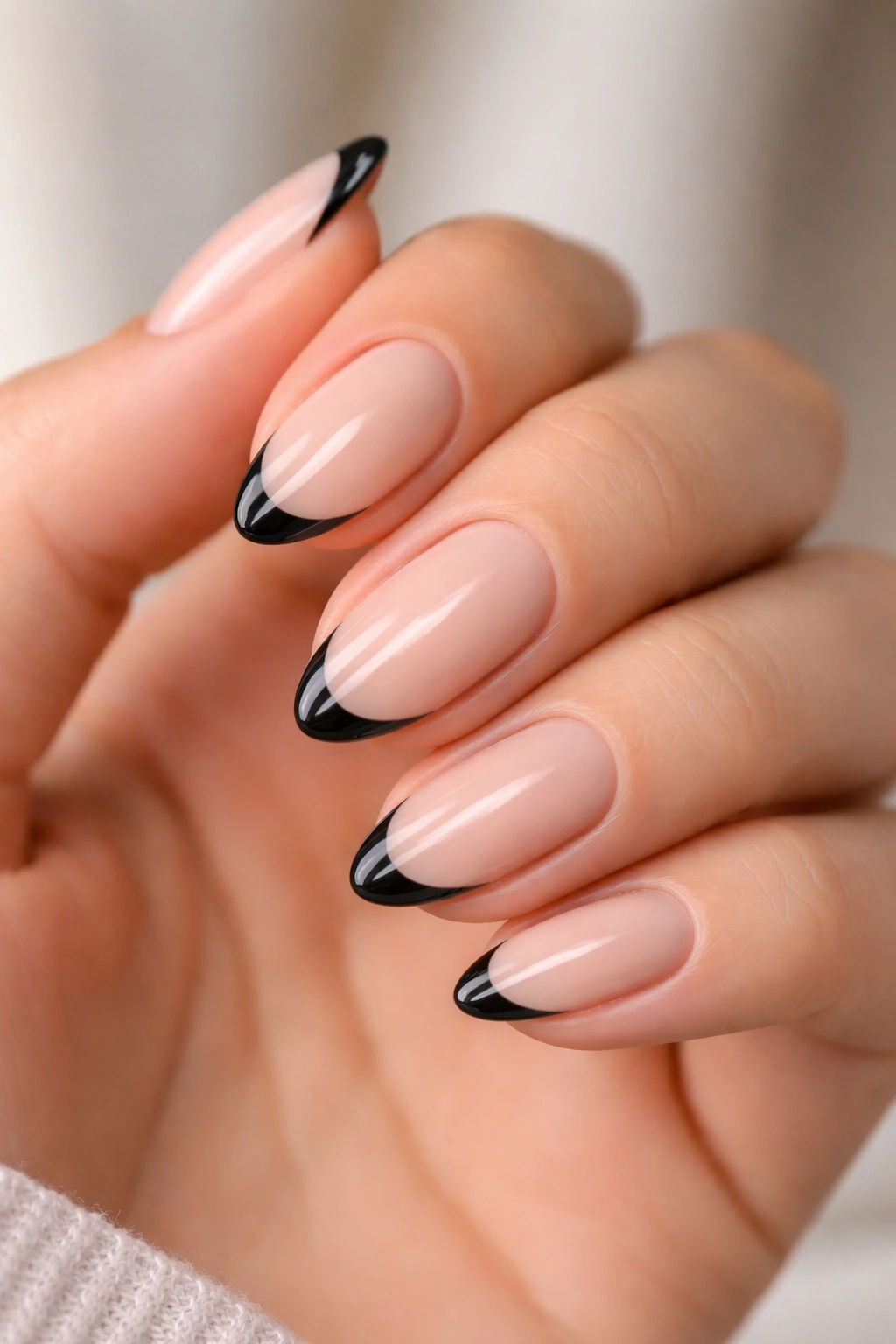 Close-up of short almond nails with a thin black micro-French smile line on nude base