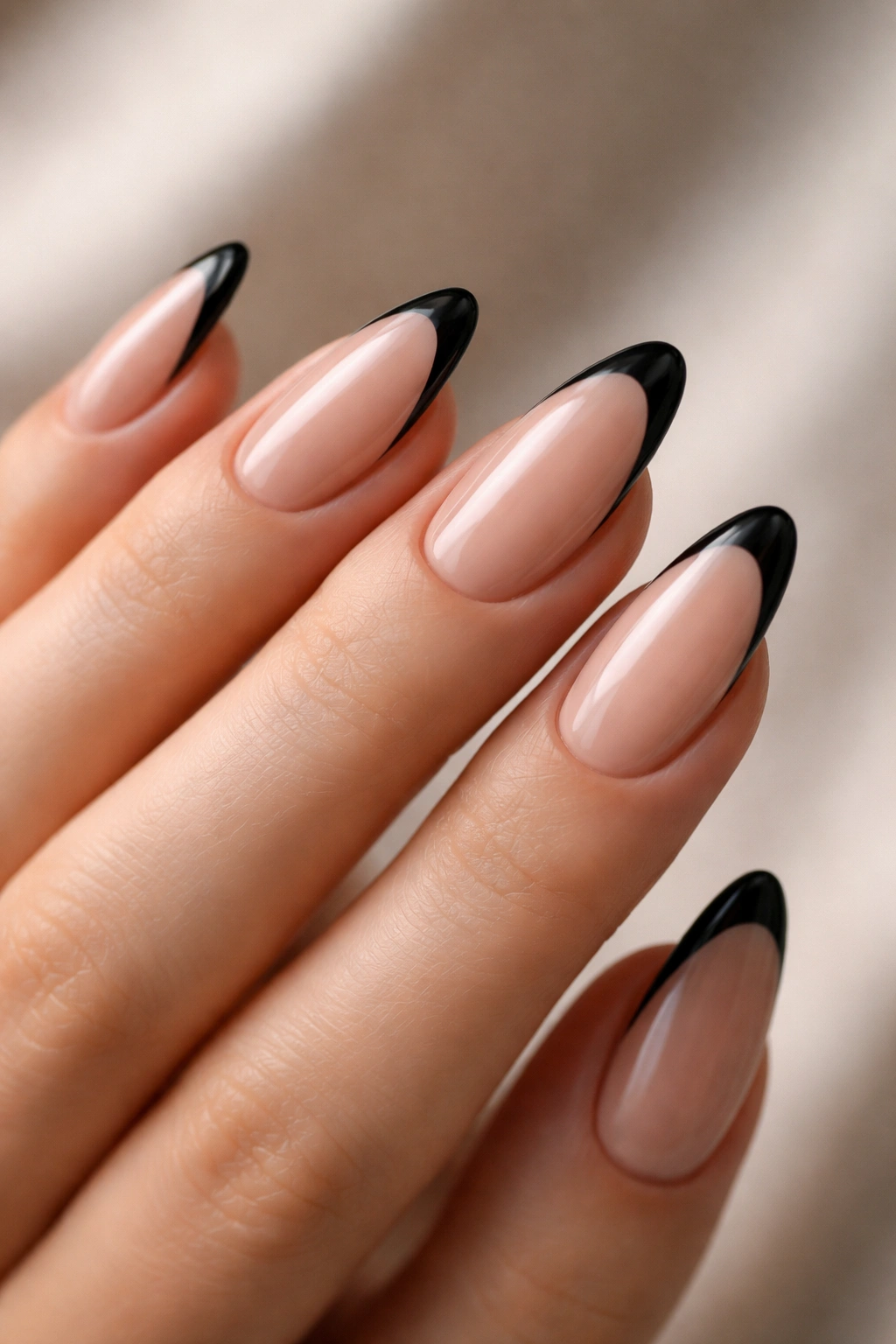 Close-up of almond nails with thin black tips on nude base