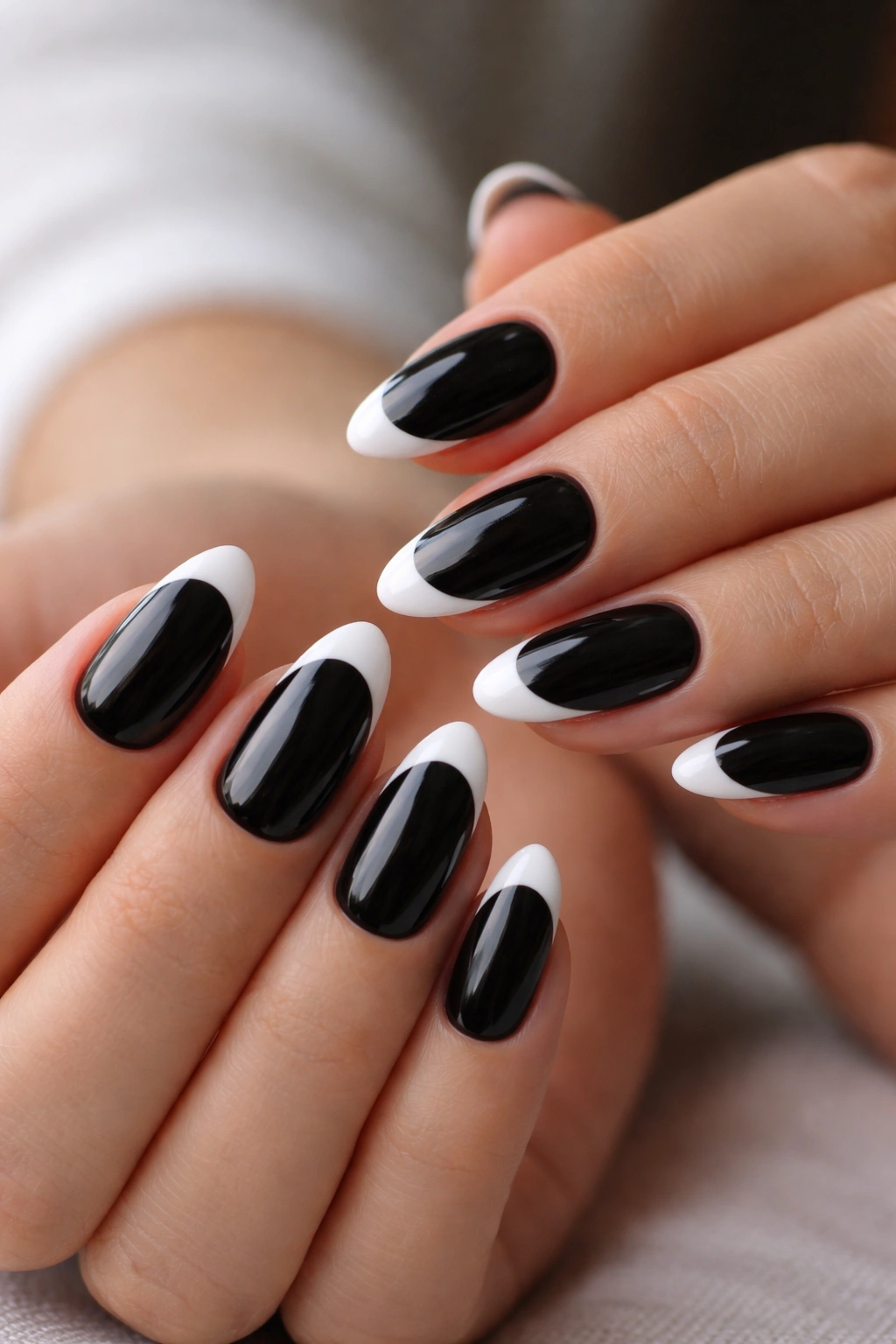 Close-up of short almond nails with black base and white tips