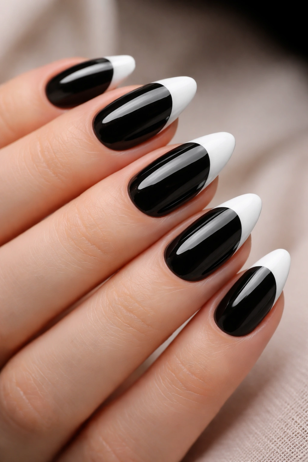 Close-up of almond nails with glossy black base and matte white tips
