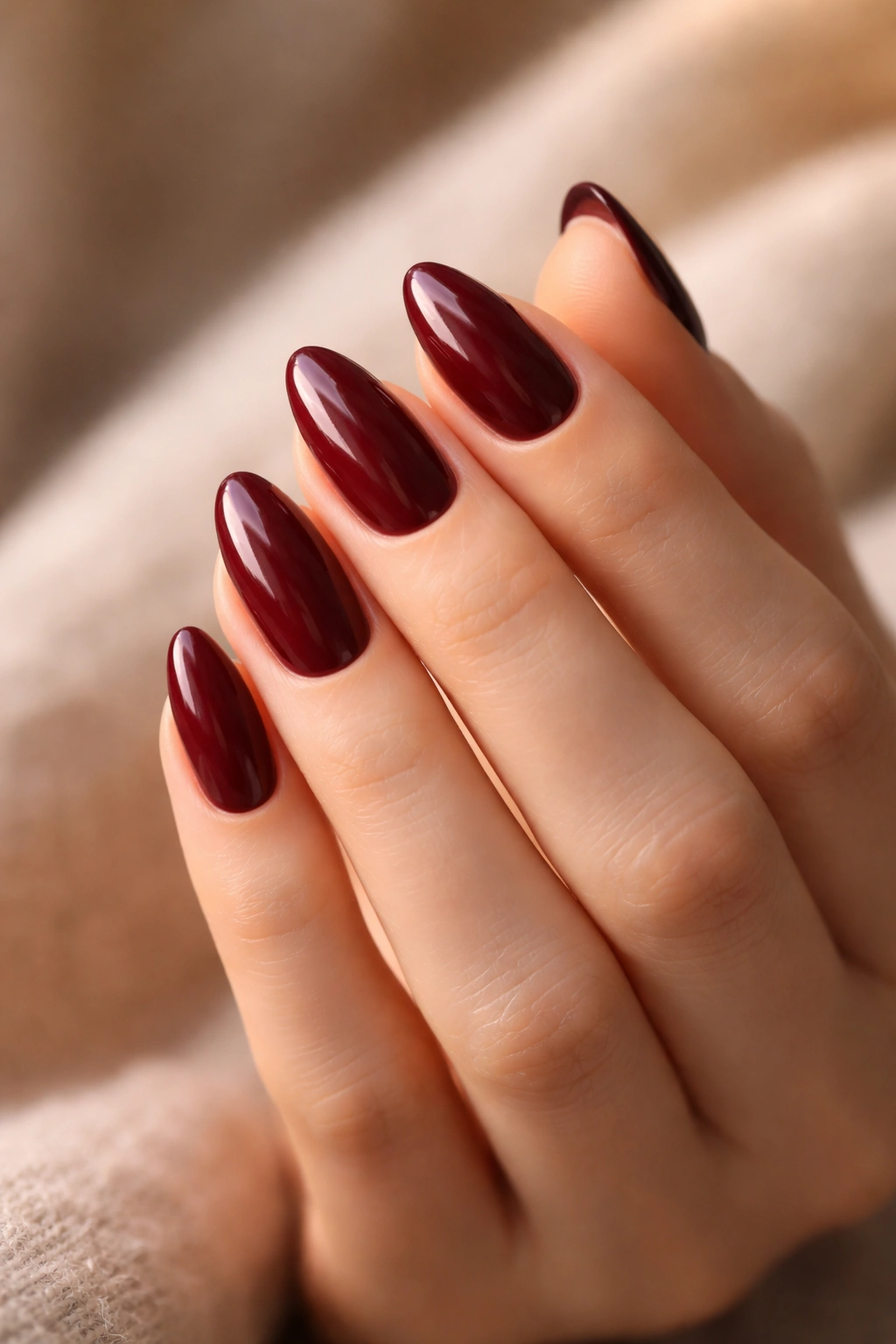 Close-up of burgundy almond nails with glossy finish