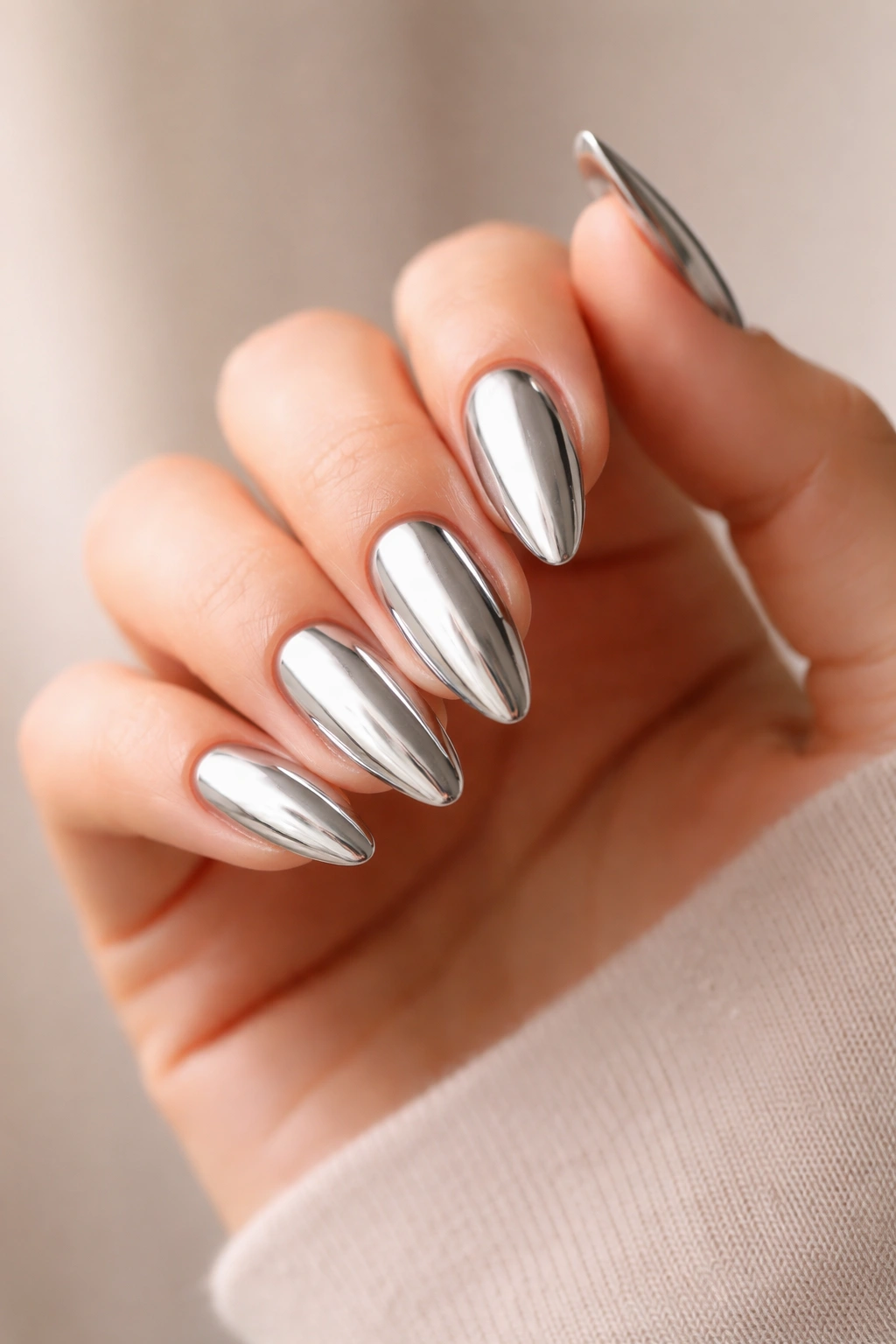 Close-up of chrome almond nails reflecting light