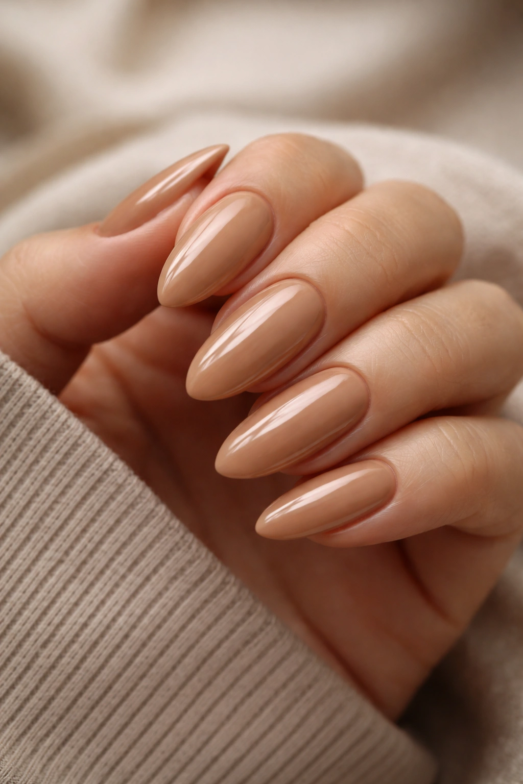 Close-up of almond-shaped creamy caramel nails with glossy finish on hands