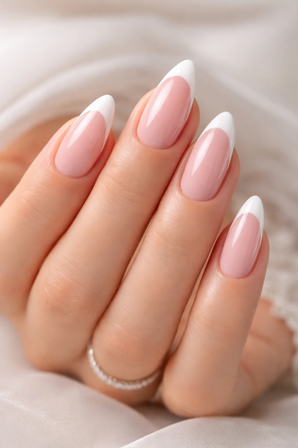 Almond-shaped nails with soft pink base and white tips on a bride's hand.