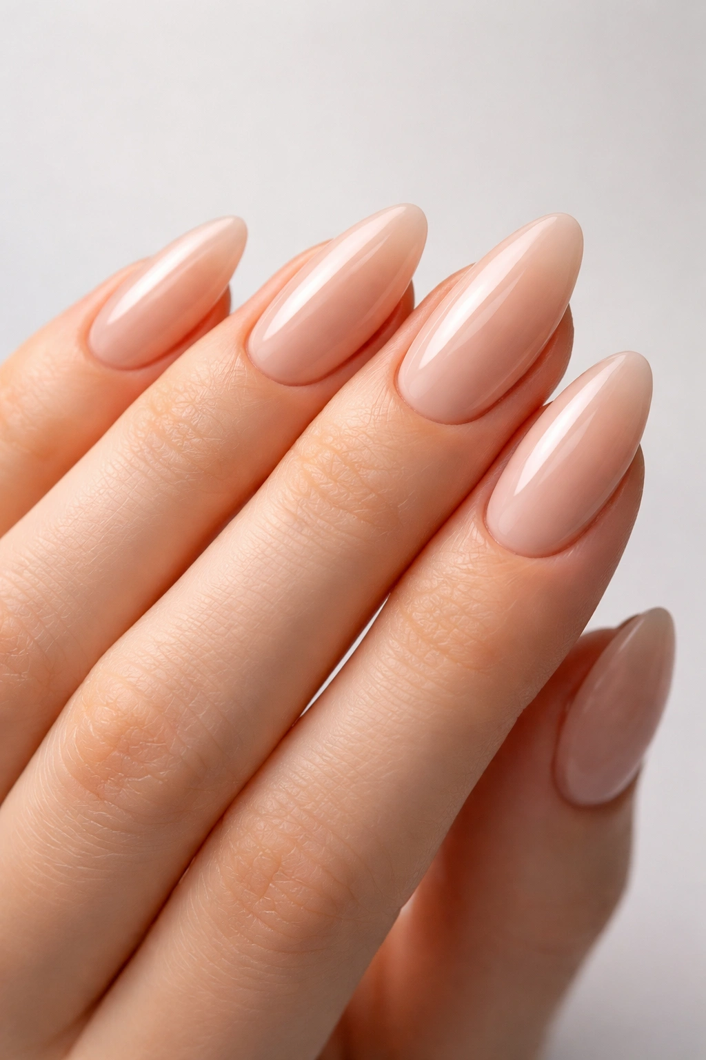 Close-up of almond-shaped nails on a hand with a nude glossy finish