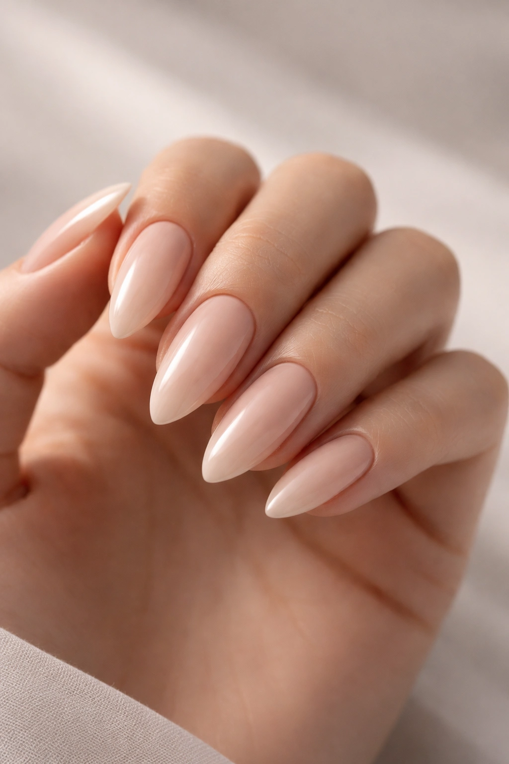 Close-up of almond-shaped nails with nude polish on a hand