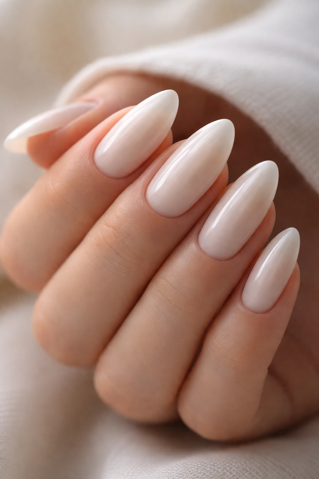 Close-up of milky white almond nails with a high-gloss finish