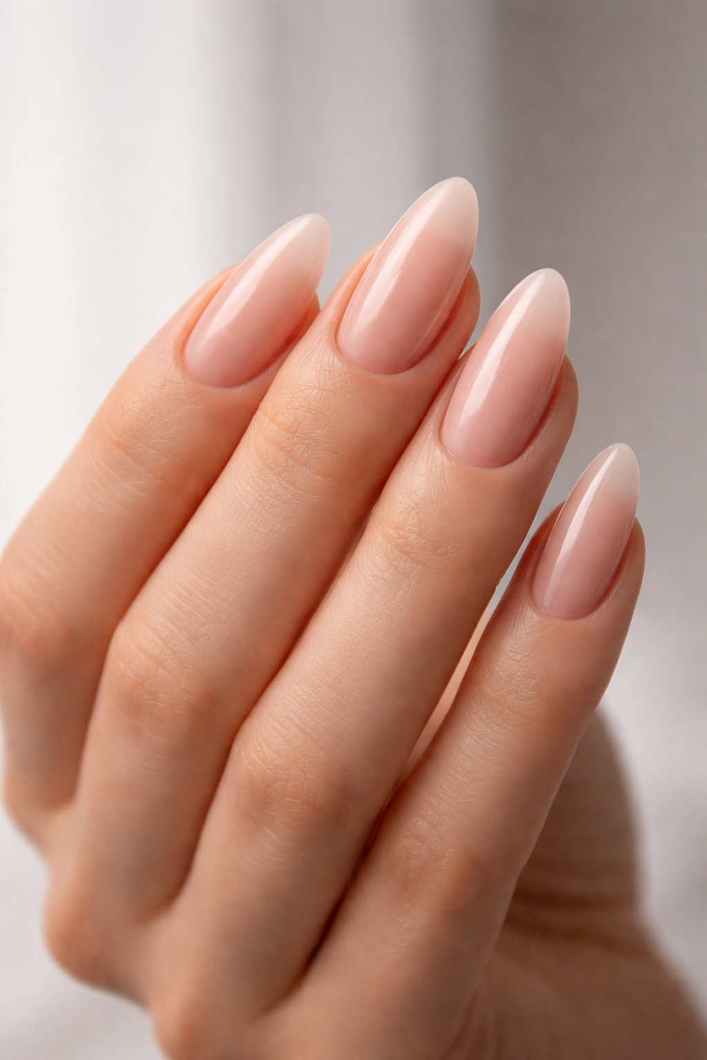 Close-up of a hand with almond-shaped nails tapering to rounded peaks