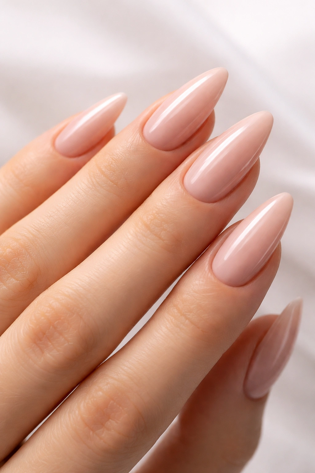 Close-up of almond nails in a sheer nude-pink manicure