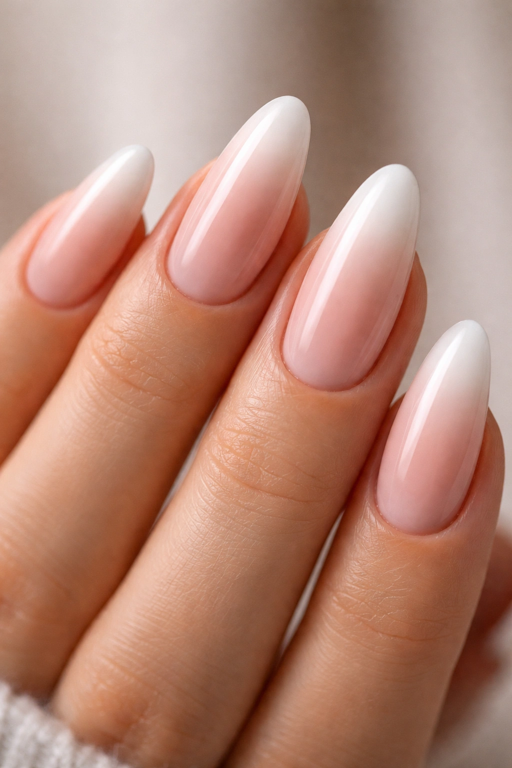 Close-up of almond nails with nude-to-white ombré gradient