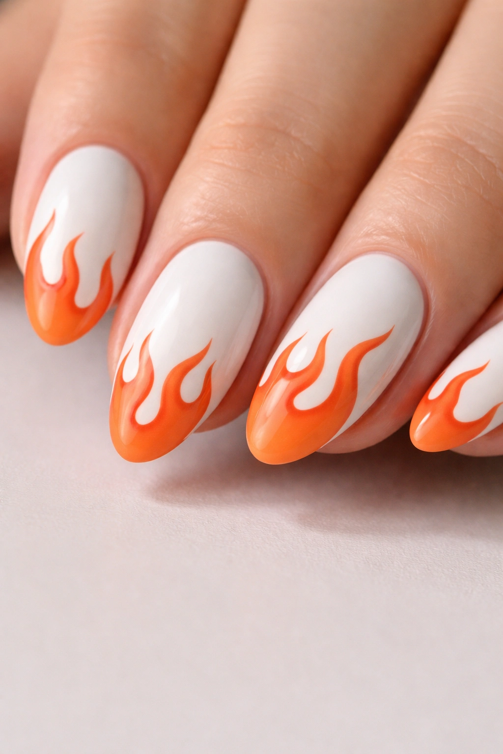 Close-up of white almond nails with orange flame tips.