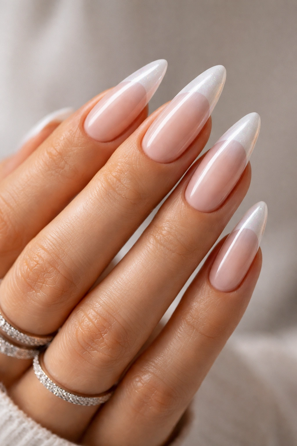 Almond nails with pearly white French tips on a nude base.