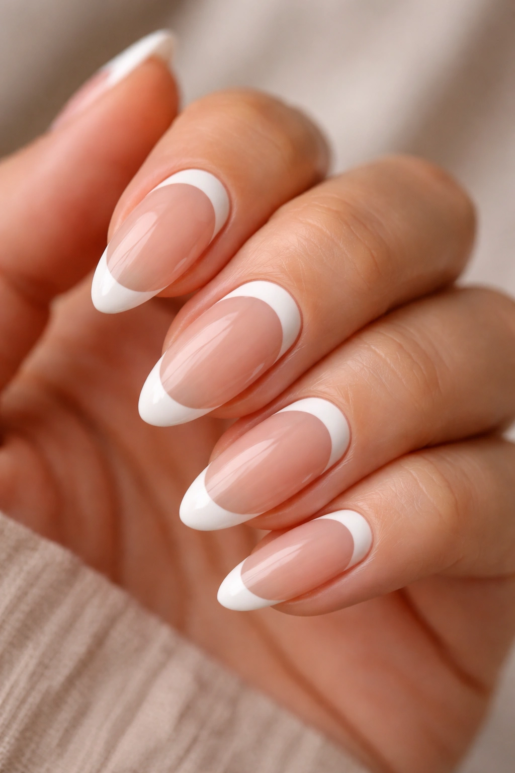 Close-up of almond nails with reverse white French tips near the cuticle