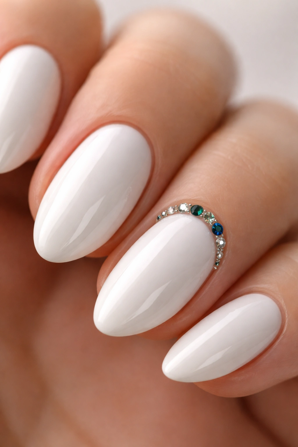 Close-up of a white almond nail with a thin jewel-tone rhinestone line.