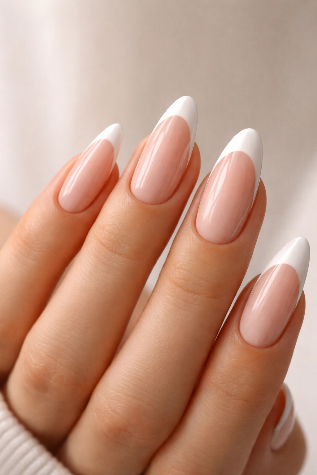 Hand with long almond nails showing different tip thickness on nude base