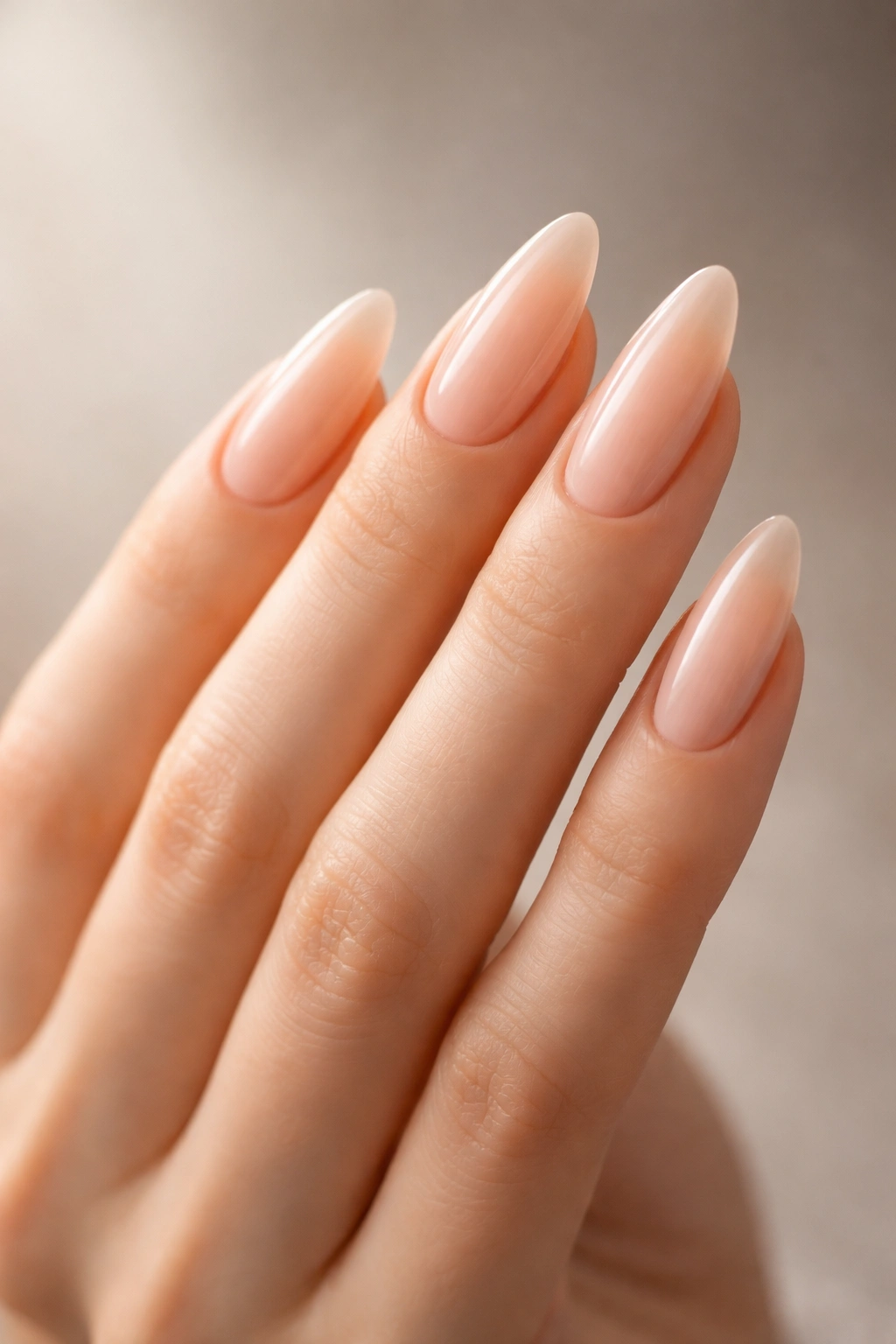 Side-profile close-up of a hand with almond-shaped nails elongating the fingers.