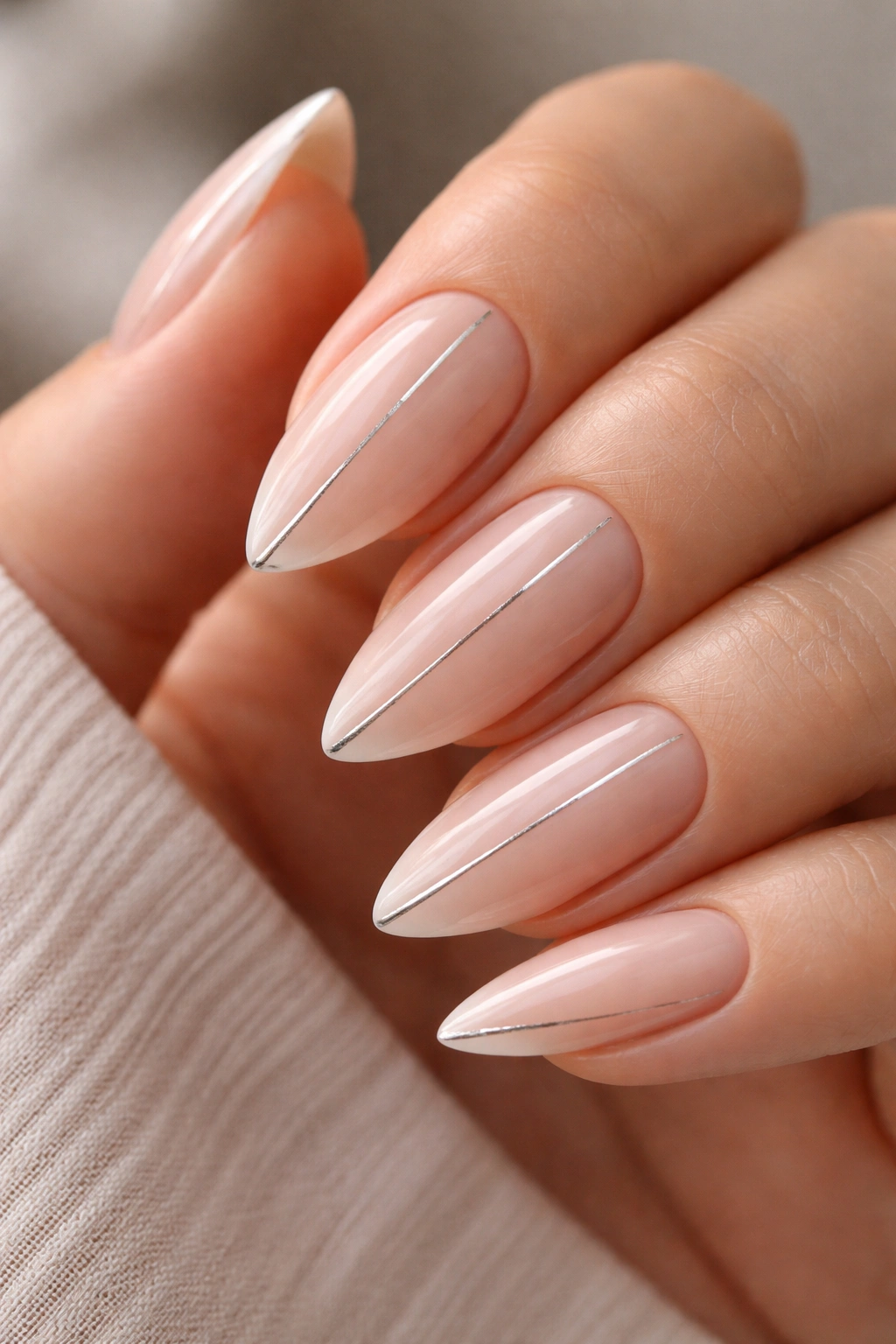 Almond nails with fine silver line accents on a nude base