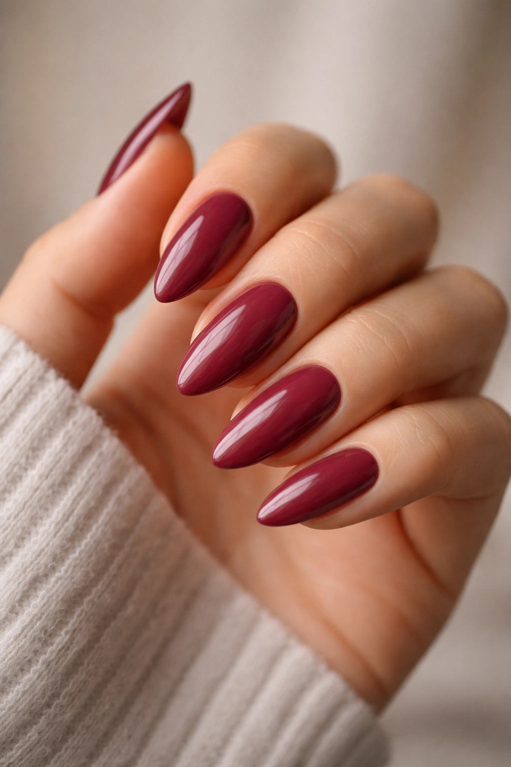 Close-up of almond nails in soft burgundy with creamy glossy finish